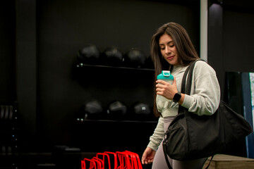 Female athlete arriving at the gym with her sports bag and shaker to do her weight training.