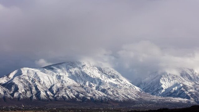 Timelapse of clouds moving over snow capped mountains looking towards Payson, Utah.