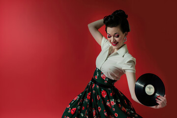 A woman in a full 1950s skirt, with bold makeup and a playful smile, dances the rock and roll