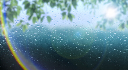 梅雨　雨の滴のついた窓ガラスと前面の木の葉とレンズフレア太陽の日差しの背景　ガラス越し奥の山林・森林の風景　6月・梅雨明け・水滴・日本・季節 - obrazy, fototapety, plakaty