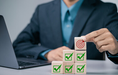 Business goal achievement concept. Businessman stacking wooden block with target goal icon and...