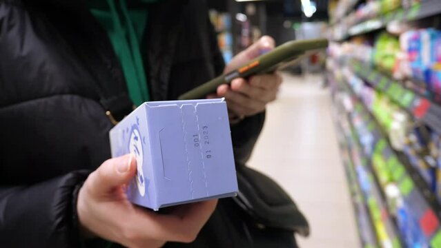 Young female customer choosing hygiene protection pads at supermarket