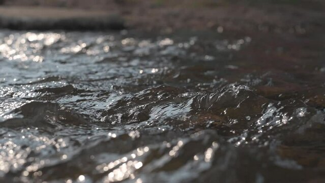 closeup of the surface of a little stream with reflecting water,Super slow motion of dark water waves in detail.