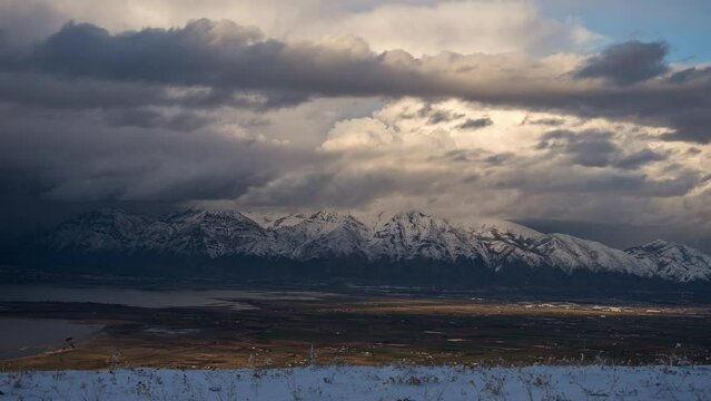 Timelapse of storm clouds moving over snow capped mountains looking across Utah Valley.
