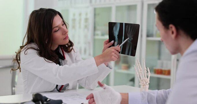 Woman doctor explains patient results of arm X-ray examination