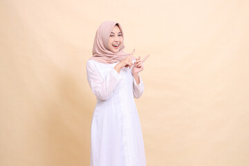 Fototapeta na wymiar woman asian muslim standing smiling cheerful both hands pointing to the top left. Fashion, pointer, business and promotion concept