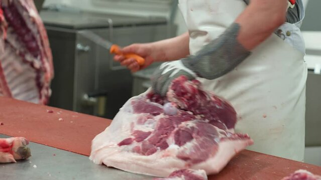 Butcher knife cutting pig flesh from slaughtered animal carcass