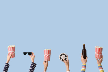 Many hands with buckets of popcorn, beer and film reel on blue background