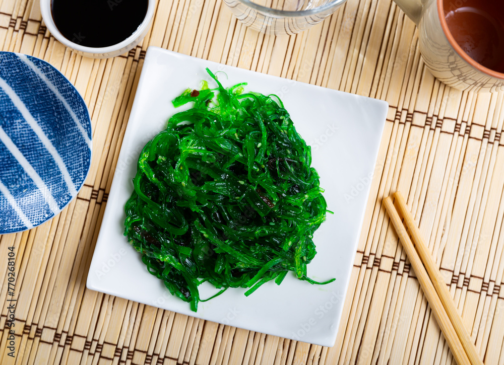 Wall mural Service plate containing Japanese algae salad with soya sauce and necessary table laying