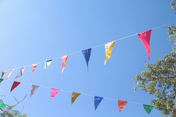 Colorful flags paper hanging on white string line abstract blue sky background
