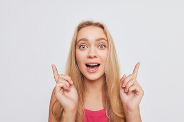 A happy woman gestures with both hands pointing up, smiling