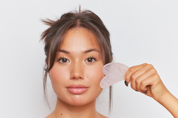 a woman is using a gua sha to massage her face