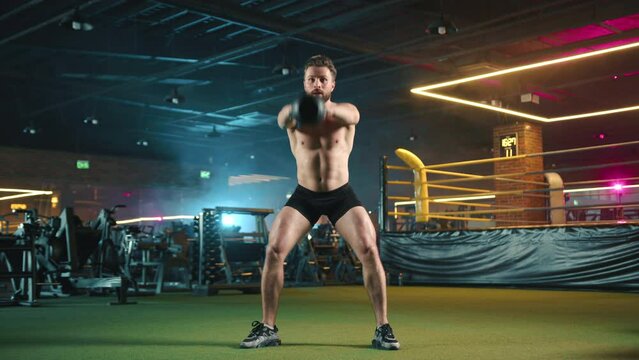 Fit male with a beard doing kettlebell swings in a modern gym, showcasing dynamic movement and physical strength under vibrant neon lighting. Camera 8K RAW. 