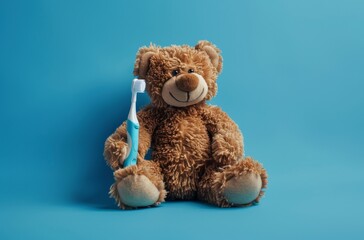 Obraz premium stuffed teddy bear with a toothbrush on a blue studio background - kids dental care concept with copyspace