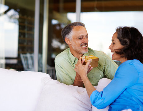 Love, happy couple and man with gift for anniversary, patio and romantic in marriage with present. Mature, people and wife by husband on honeymoon, gratitude and care for bonding together on holiday