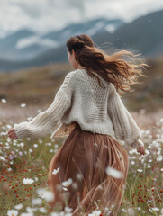 a girl walks in flowery mountain meadows in a cozy sweater and silk skirt, Generative AI 