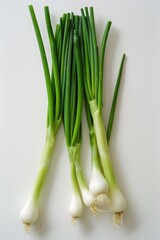 A bunch of green onions are sitting on a white counter. The onions are fresh and ready to be used in a meal