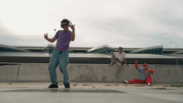 Group of asian break dancer perform street dance with multicultural friend support and moving hip hop music. Attractive handsome hipster practice b boy dance at street. Outdoor sport 2024. Sprightly.
