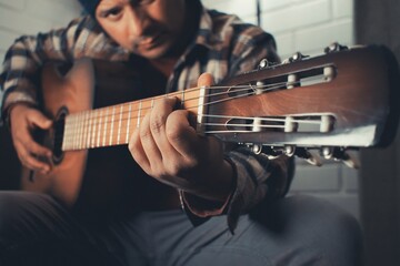 man practicing acoustic guitar at home