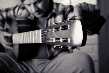 man practicing acoustic guitar at home, black and white photography