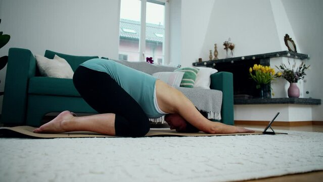 Pregnant woman exercising at home in living room floor, taking care of back pain during third trimester pregnancy