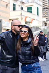  Happy smiling beautiful  Tourists  couple traveling in Italy poses and making photos near the Cathedral of Amalfi  .Family on vacation on Amalfi coast in Italy. 