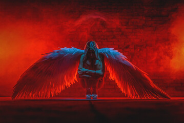 Beautiful girl an angel with white wings posing on the dark background. Angel of the dark concept.