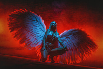 Beautiful girl an angel with white wings posing on the dark background. Angel of the dark concept.