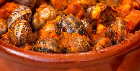 The boiled snails in tomato sauce with garlic and chili in iron pan