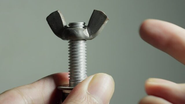 Turning and Fasten a Steel Wing Bolt Screw By Hand and Finger, Close Up