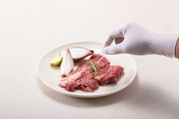 Sprinkling salt on beef on a white plate
