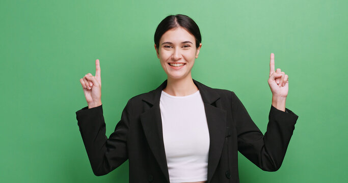Happy young business woman showing something or copy space for product or sign text. Isolated on green background in studio.