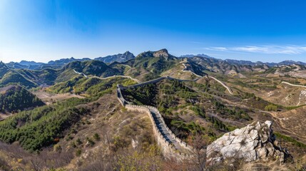 Fototapeta na wymiar The Great Wall of China winding through a rugged mountain landscape under a clear blue sky. 