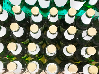 Many green beer bottles in a row, top view, close up