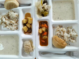 A set of various kinds of food in a white plastic box.