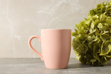 A pink cup with green hydrangeas in a vase