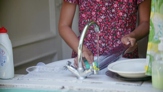 Housewife scrubbing away dirt and grime on dishes with sponge	