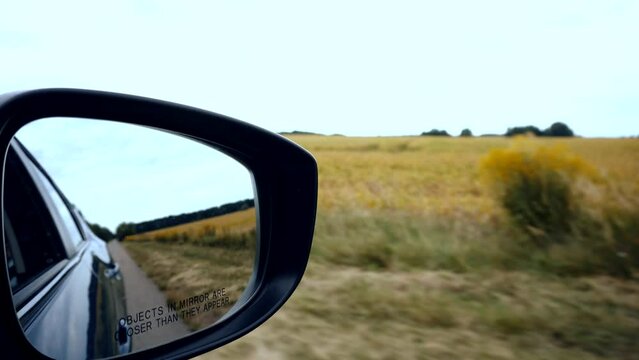 Driver's side rearview mirror reflects movement of car during trip