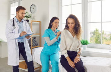 Woman nurse with stethoscope examining female patient lungs, breathing and heartbeat at the...