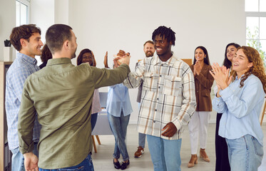 Diverse group of friends standing in a circle during meeting, expressing success. With smiles they...