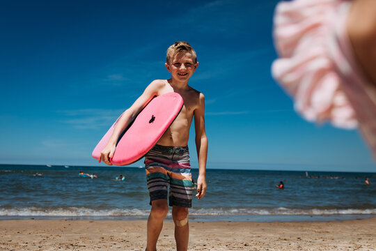 Smiling child on beach of Lake Michigan holding boogie board