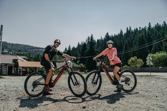 Happy young couple riding their electric bicycles in the nature