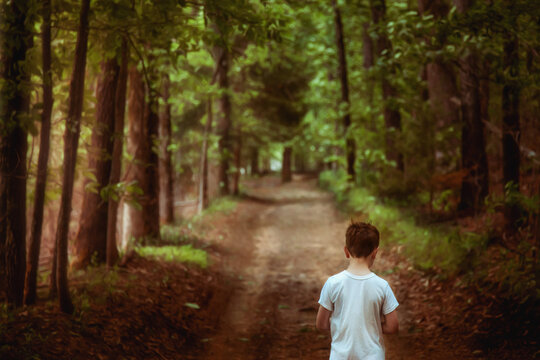 Boy walking along a wooded path with sunlight streaming in