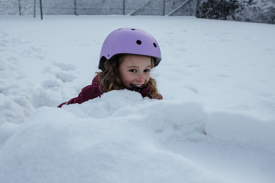girl hiding in the snow whilst ice skating outdoors