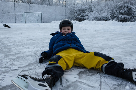 boy laying on the ice ice skating outside