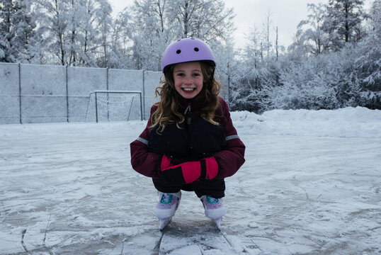 girl on an outdoor ice rink smiling in the snow