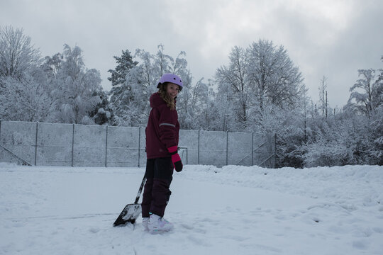 girl with a snow shovel ice skating outside