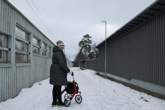 retired woman happily walking in the snow with her rollator