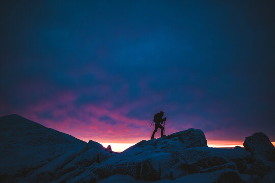 Hiker silhouetted against sunrise in winter in White Mountains, NH