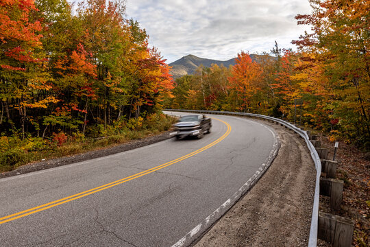 Speeding vehicle with curvy mountain road and vibrant autumn leaves - Powered by Adobe